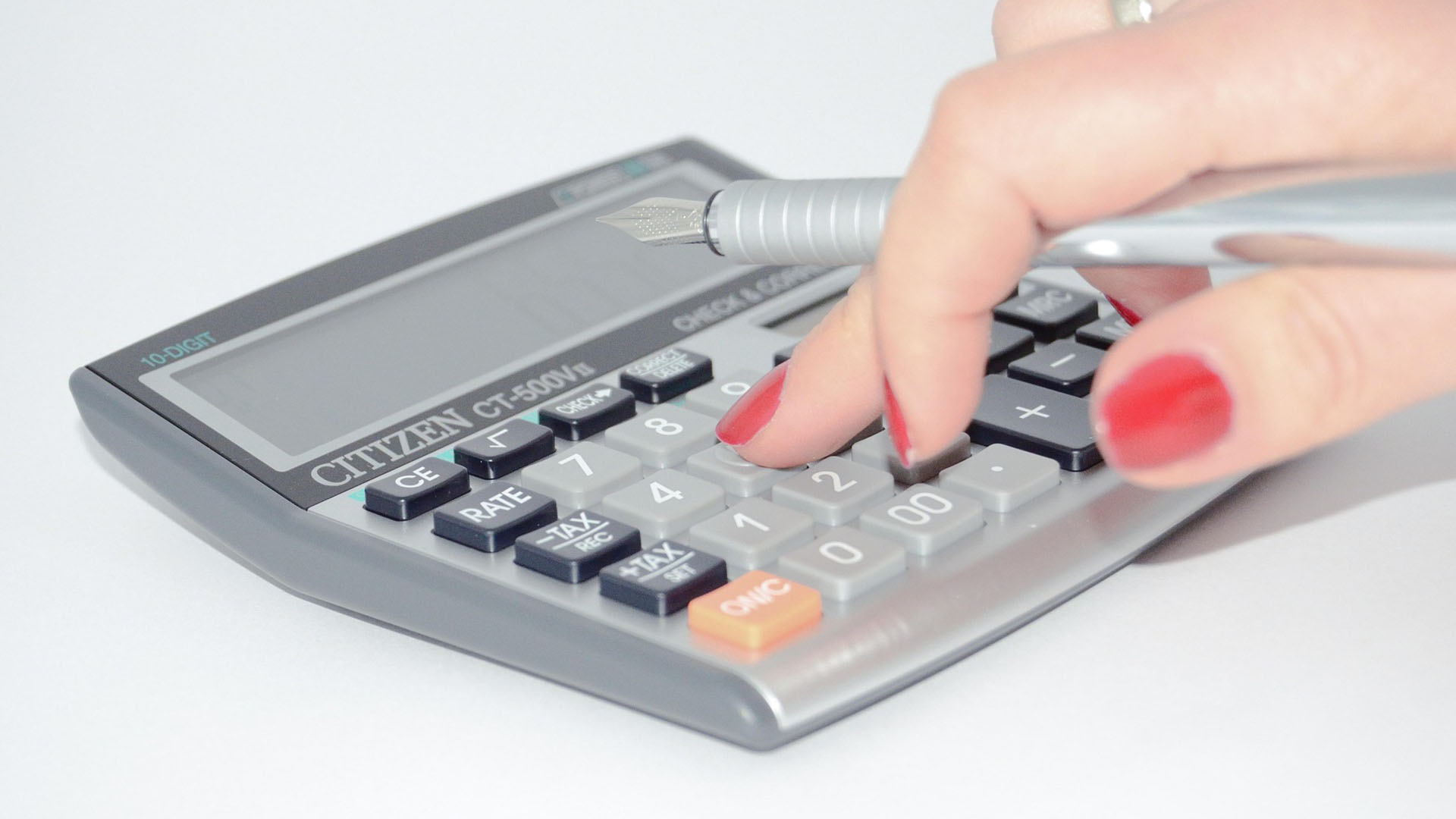 Personne calculant son imposition 2025 avec une calculatrice et son stylo